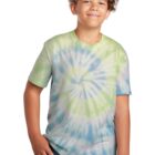 Smiling boy in a tie-dye shirt and jeans standing against a white background.