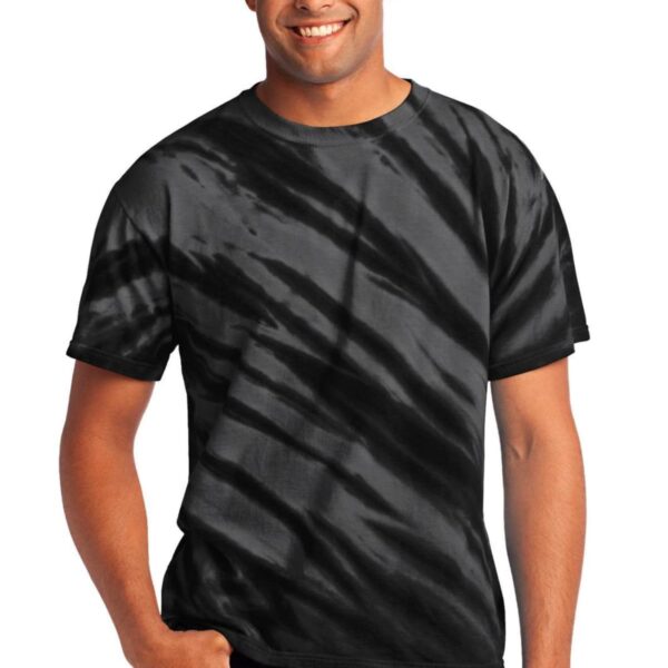 Man wearing a black tie-dye t-shirt and jeans, smiling with hand in pocket.