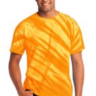Person wearing an orange tie-dye shirt and jeans, smiling with hands in pockets.