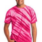 Person wearing a pink tie-dye t-shirt, smiling, and standing with their hand in a pocket.