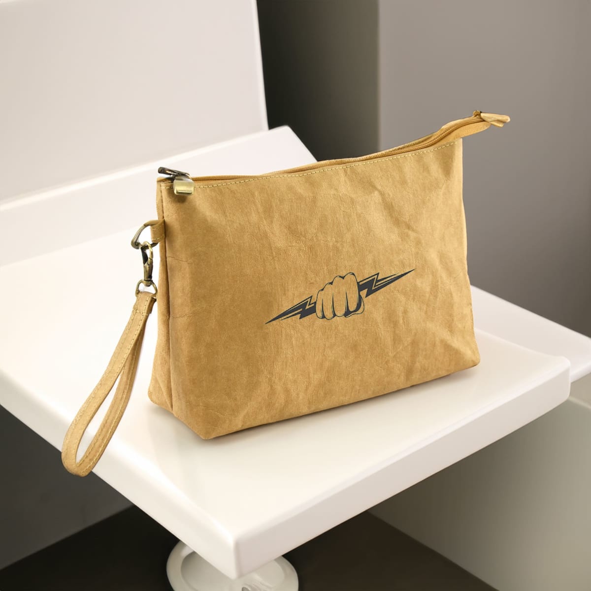 Tan clutch bag with a zipper and wrist strap, featuring a fist and lightning bolt design.