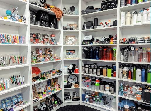 Shelves filled with colorful promotional products like pens, mugs, and unique gift items.