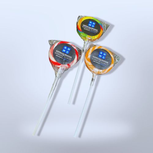 Three colorful lollipops with clear wrappers and white sticks on a light background.