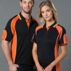 Two people wearing matching black and orange sports shirts, posing against a gray background.