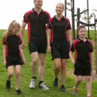 A family of four in matching outfits walking on grass together.