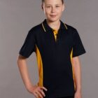 Boy in a black and yellow polo shirt, standing with hand on hip against a gray background.