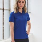 Person standing in a blue polo shirt and black pants near a window.