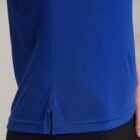 Close-up of a person wearing a blue shirt with black pants, hand resting at the side.