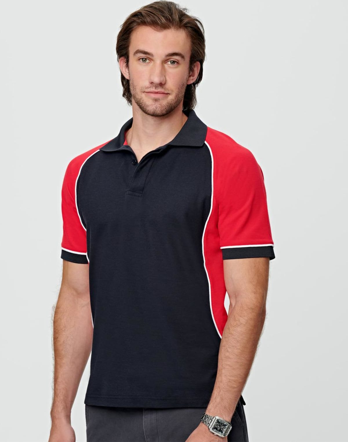 Man in a black polo shirt with red sleeves standing against a plain background.