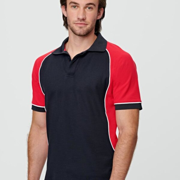 Man in a black and red polo shirt standing against a light gray background.