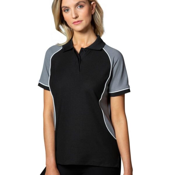 Woman in black and gray polo shirt, standing against a white background.