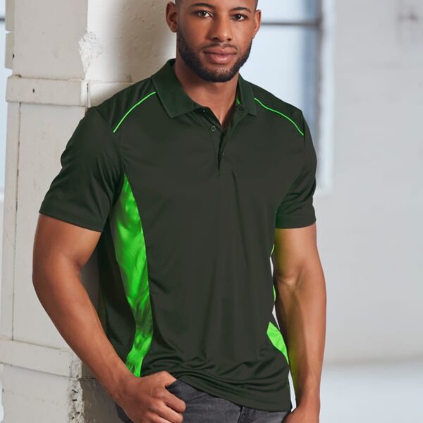 Man in a dark green polo shirt with bright green accents, leaning against a wall.