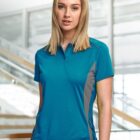 Person in a blue polo shirt standing indoors near stairs.