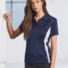 Woman in a navy polo shirt with white stripes, standing indoors.