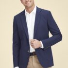 Man in blue blazer and white shirt, smiling against a beige background.