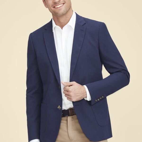 Man in blue blazer and white shirt, smiling against a beige background.