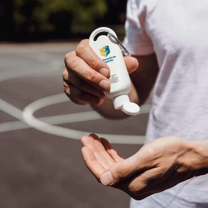 Person squeezing sunscreen onto hand, debunking common sunscreen myths at a basketball court.