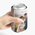 Hand holding a can in a cozy with a couples wedding photo.