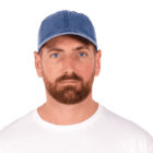 Man with a brown beard wearing a blue cap and white shirt on a white background.