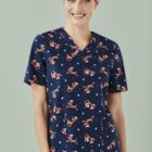 Smiling woman wearing a navy blue scrub top with Santa print.