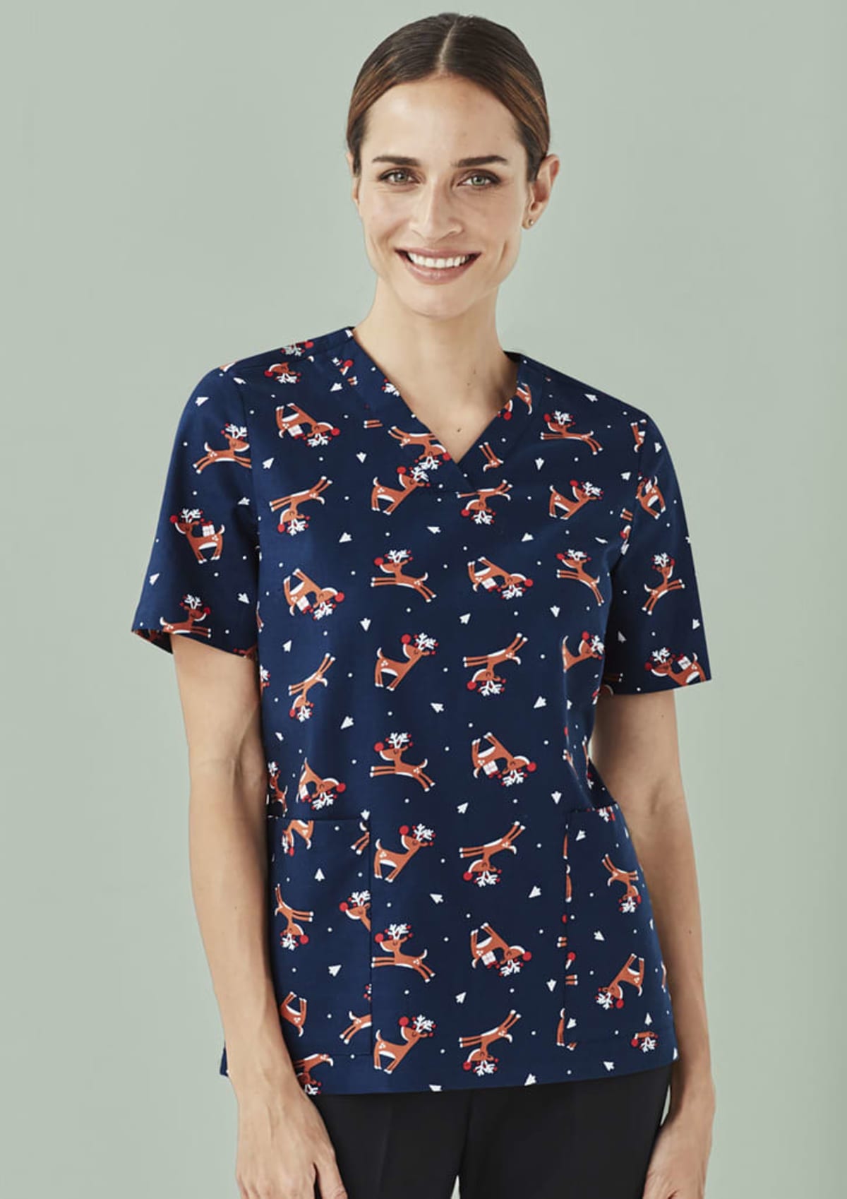 Smiling woman wearing a navy blue scrub top with Santa print.