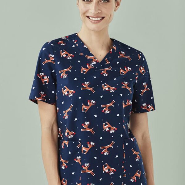Person wearing a blue scrub top with a skiing pattern and smiling.
