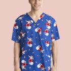 Person wearing blue scrubs with cartoon Santa pattern, standing and smiling.