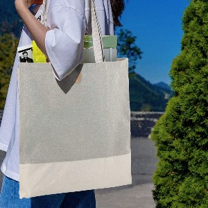 Person outdoors at street fairs carrying a light-colored tote bag with books and items inside.