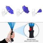 A person opens a blue umbrella using a manual button on the handle.