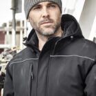 Man in a black jacket and gray beanie looking into the distance, with a blurred urban background.
