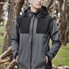 Person in a gray and black jacket standing in a forested area.