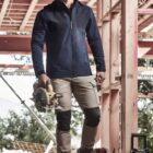 Person in work attire with a power saw at a construction site.