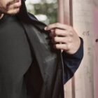 Person examining the mesh lining of a jacket in a partially constructed building.