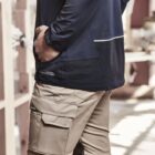 Person wearing a dark jacket and cargo pants in a workshop.