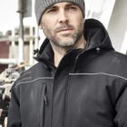 Man wearing a gray beanie and black jacket, standing outdoors.