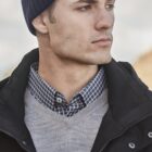 Man in beanie and layered clothing looks to the side.