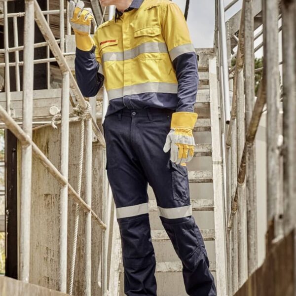 Worker in safety gear on industrial site, using a handheld device.