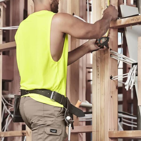Man in yellow tank top using tools on wooden structure.