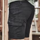 Person wearing black cargo shorts and a green shirt stands near wooden structure.