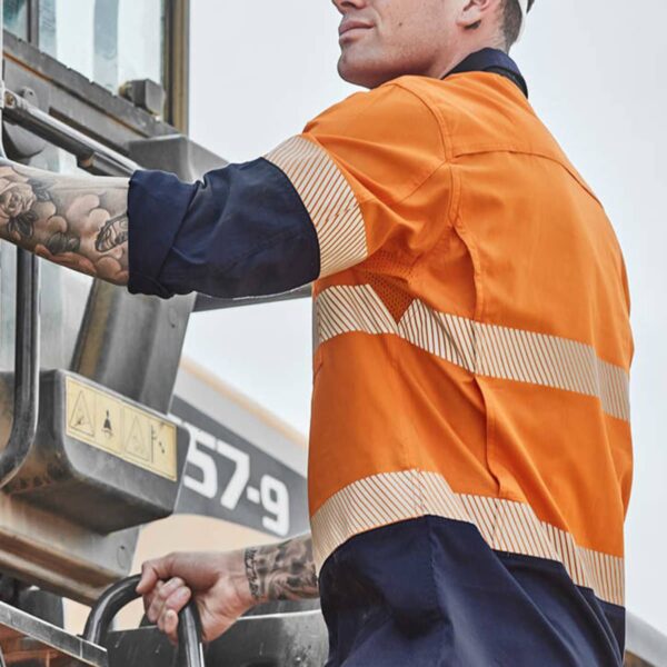 A male construction worker in safety gear climbs into a vehicle.