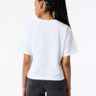 Person with braided hair in a white t-shirt and black jeans, seen from behind.