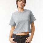 Woman in a gray cropped t-shirt and black jeans standing with hands in pockets.