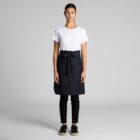 Person wearing a white t-shirt, black apron, black pants, and black shoes standing facing forward.