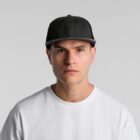 Man in white t-shirt and dark cap looking straight at camera against a plain background.