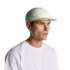 Man in a white T-shirt and light-colored cap looking to the side against a white background.