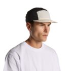 Man in a white t-shirt wearing a black and white cap, looking to the right.