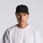 Man in a black baseball cap and white t-shirt looking seriously at the camera.