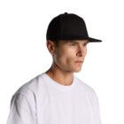 Man in a white shirt wearing a black baseball cap, looking to the side against a white background.