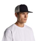 A man in a white shirt and black mesh trucker hat looks to the side against a white background.