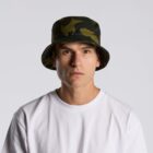 Man in a white shirt wearing a dark green camouflage bucket hat, facing forward.